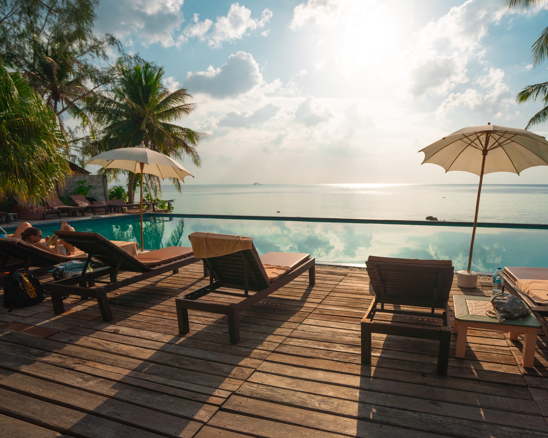 A photo of a swimming pool and deck chairs by the sea.