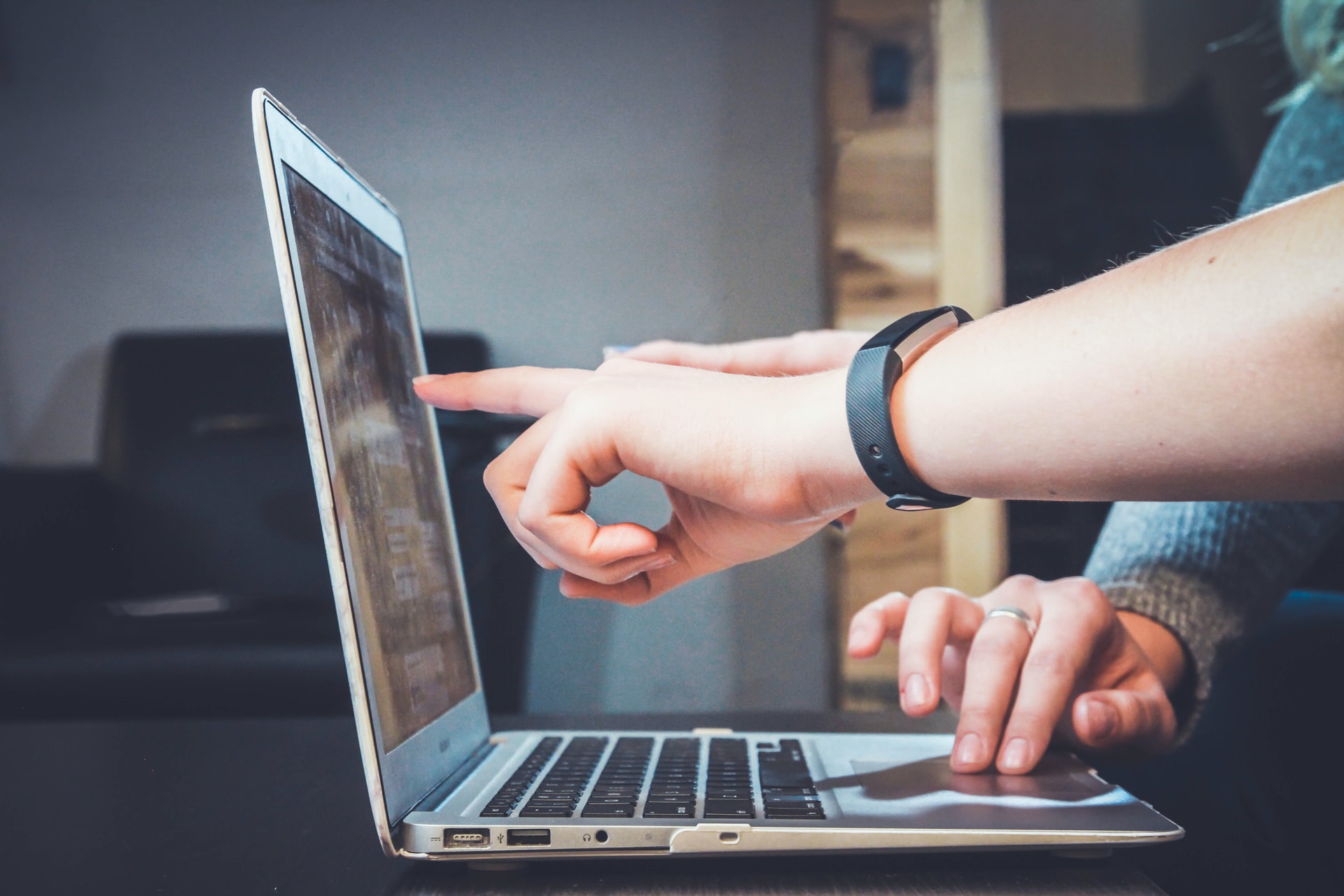 Photo of a person pointing to a laptop.